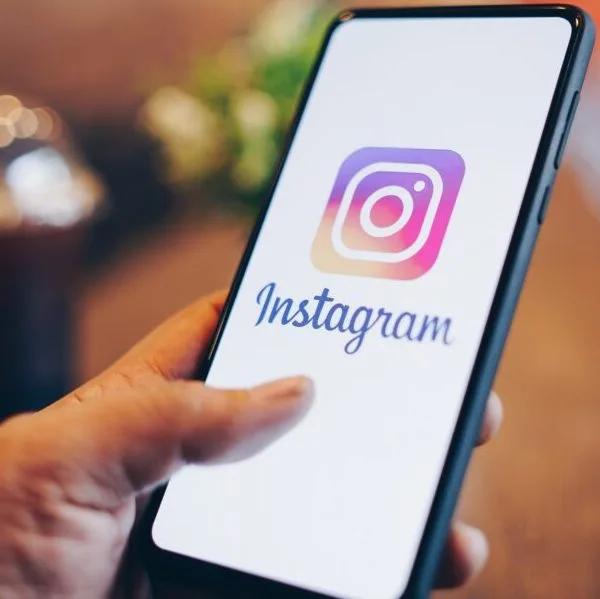 A hand selecting the Instagram app on a phone.